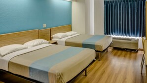 A hotel room with two beds, wooden headboards, a window with curtains, and an air conditioning unit. - Motel 6 Katy, TX - Houston (Katy)