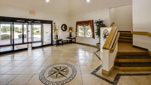 A spacious lobby with a tiled floor, a staircase, and a large glass door entrance. - Motel 6 Katy, TX - Houston (Katy)