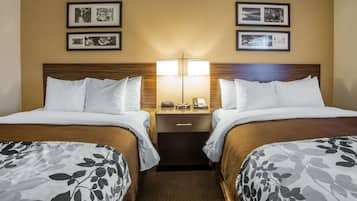 A hotel room with two beds, a nightstand with a lamp, and framed pictures on the wall.