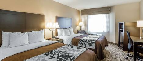 Habitación de hotel con dos camas, un escritorio, una silla y un televisor.