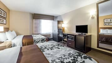 Una habitación de hotel con dos camas, un escritorio con televisor, un espejo y una ventana con cortinas.