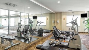 A gym with various exercise machines, a clock on the wall, and a large window providing natural light. - Sleep Inn Provo near University (Provo)