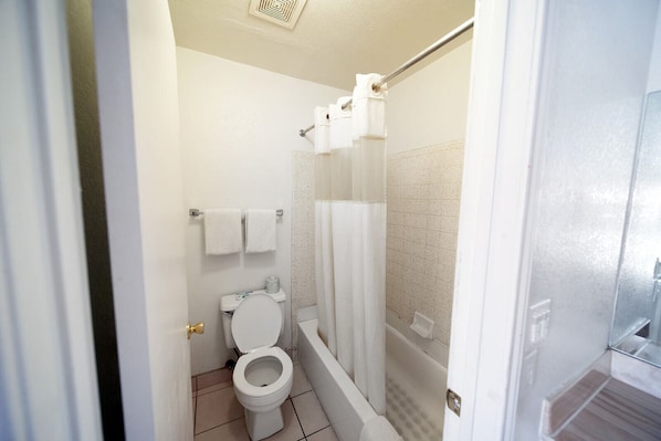 A bathroom with a toilet, a shower with a glass door, and a towel rack with two towels.