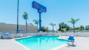 A clear blue swimming pool with lounge chairs and a sign indicating free WiFi. - Motel 6 Bakersfield, CA - Central (Bakersfield)