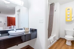 Une salle de bain avec un lavabo blanc, un plan de toilette noir et des toilettes blanches.