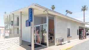 A small, single-story building with a glass door entrance, a sign indicating 'Office 6', and vending machines outside. - Motel 6 Bakersfield, CA - Central (Bakersfield)