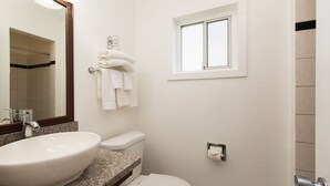 A bathroom with a white sink, toilet, and a window. - Signature Inn Merced Yosemite Parkway (Merced)