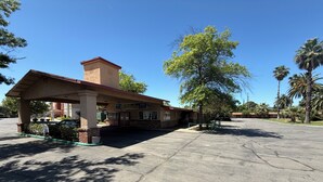 A gas station with a canopy, a brick building, and palm trees in the background. - Oroville Value Suites (Oroville)