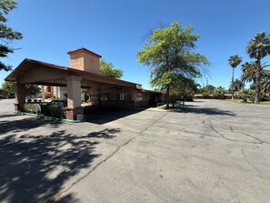 A gas station with a canopy, a brick building, and palm trees in the background.