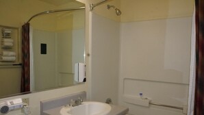 A bathroom with a sink, mirror, towel rack, and shower. - Oroville Value Suites (Oroville)
