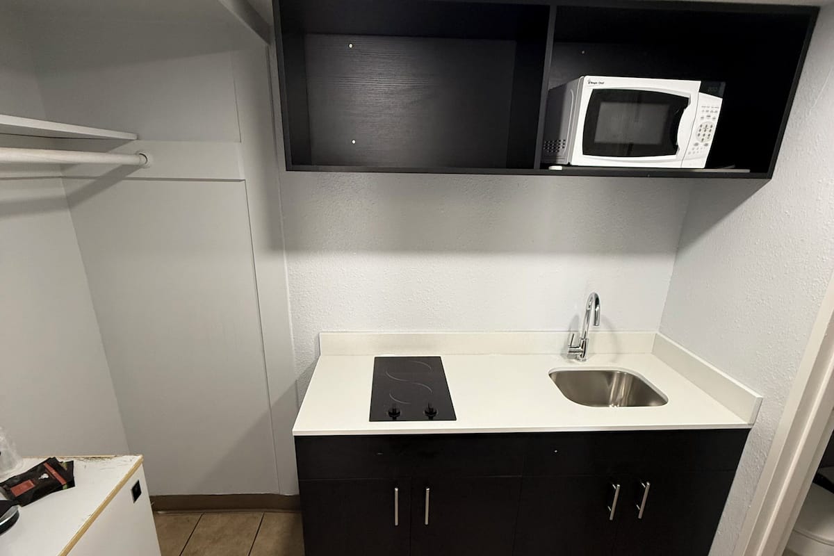 A compact kitchen with a microwave, sink, and cabinets.