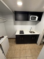 Una cocina compacta con microondas, pileta y placares.