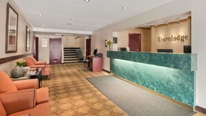 A reception area with a marble counter, a staircase, and seating with a patterned carpet.