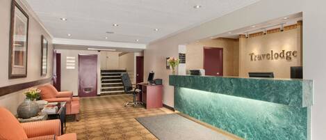A reception area with a marble counter, a staircase, and seating with a patterned carpet.