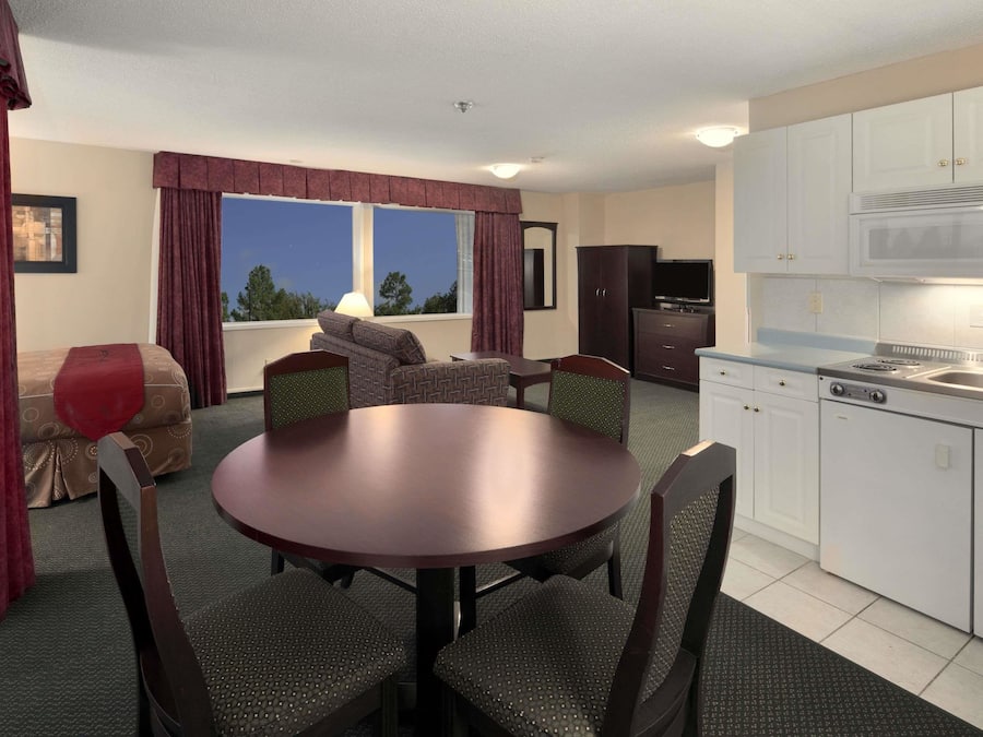 A compact living space with a dining table, chairs, a sofa, and a kitchenette.