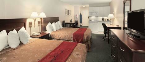 A hotel room with two beds, a desk, a chair, a television, and a kitchenette.