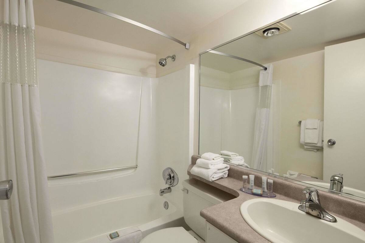 A modern bathroom with a bathtub, a sink, and a large mirror.