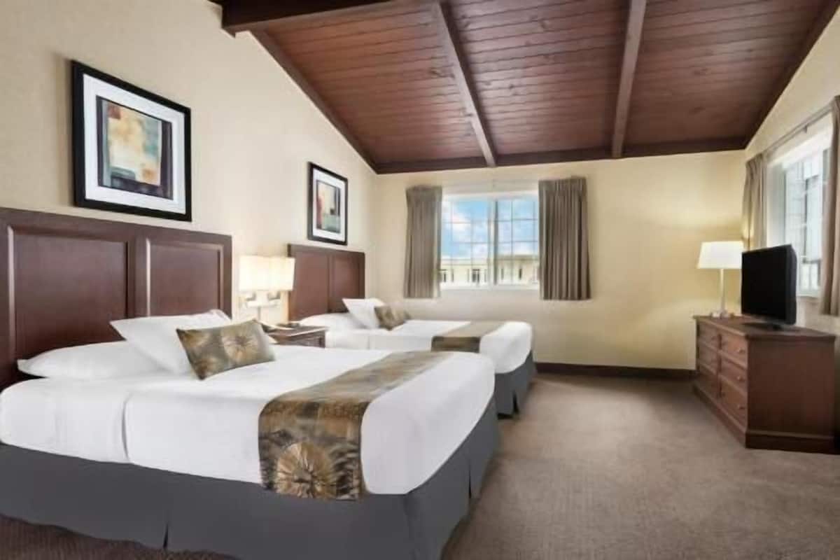 Een hotelkamer met twee bedden, een televisie, een dressoir en een raam met gordijnen.