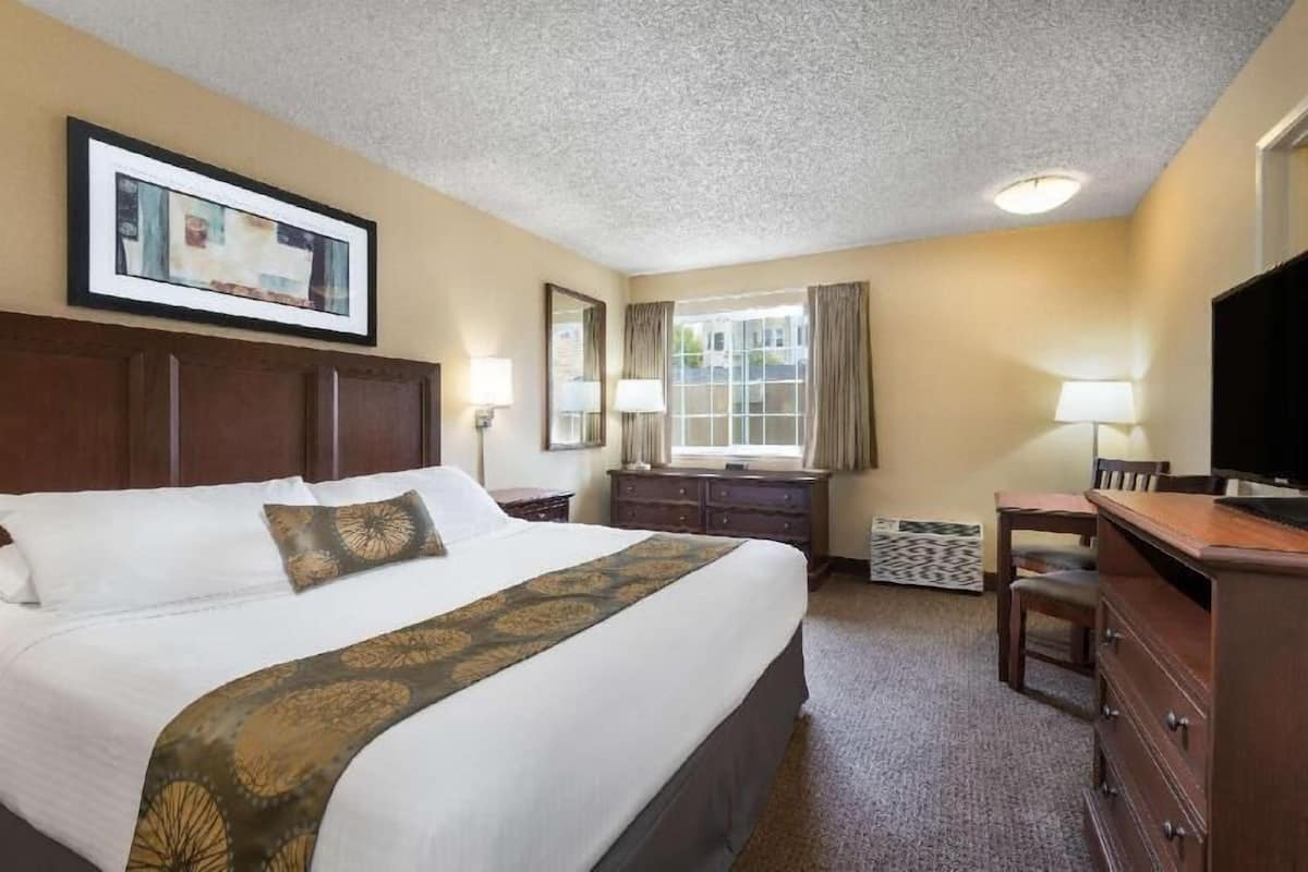 Een hotelkamer met een groot bed, een bureau, een televisie en een raam met gordijnen.