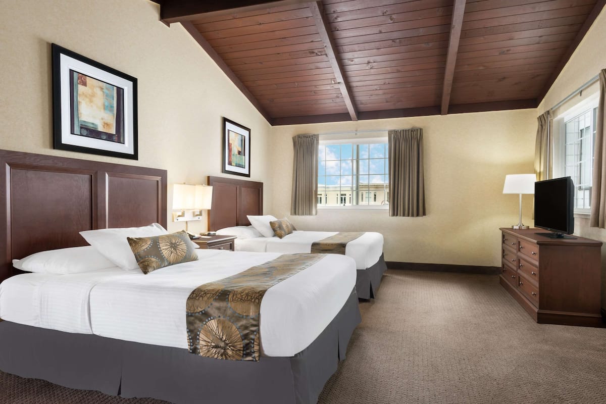 Een hotelkamer met twee bedden, een televisie, een dressoir en een raam met gordijnen.