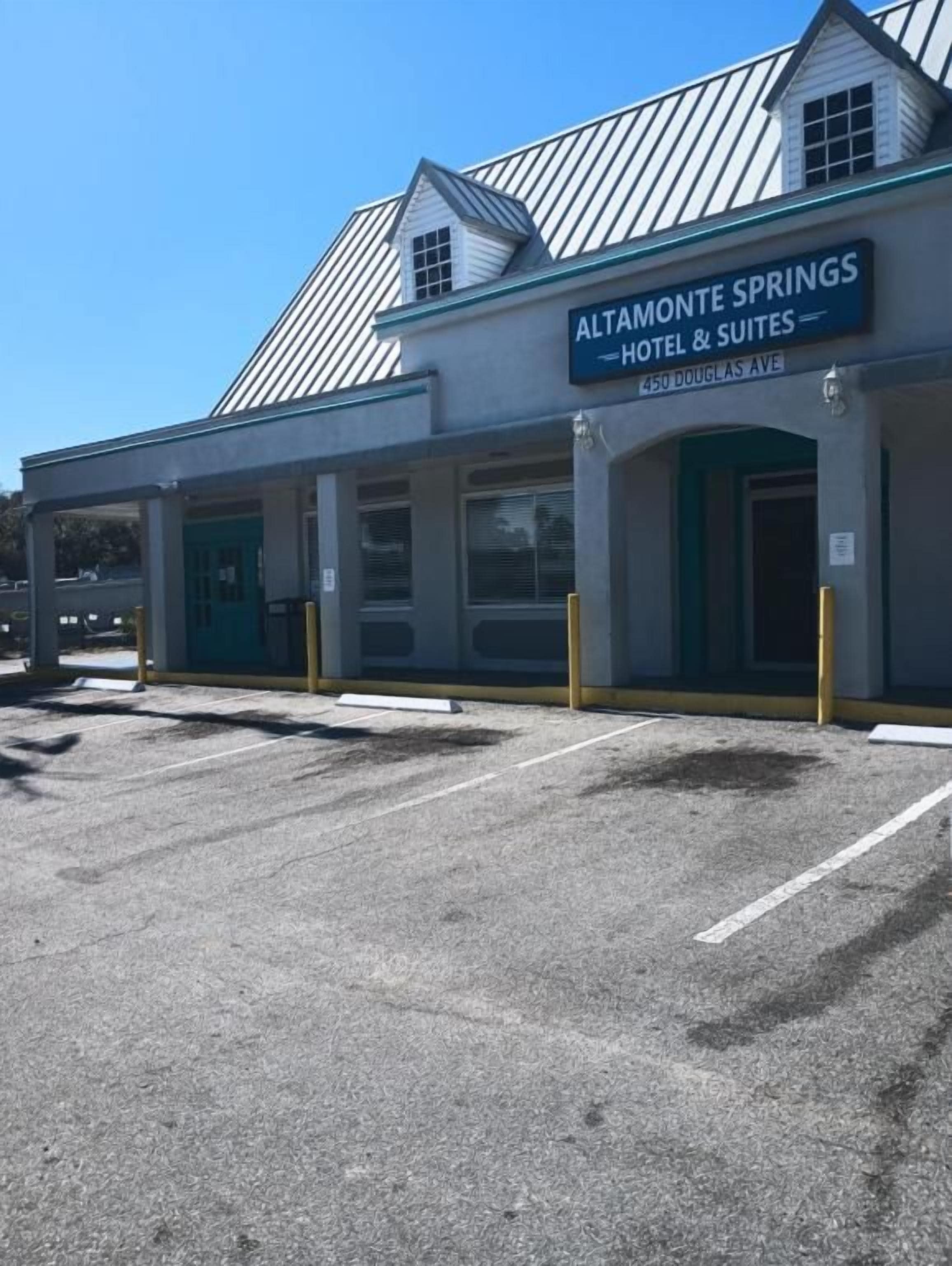 A hotel with a sign reading 'Altamonte Springs Hotel & Suites.' There are parking spaces in front.