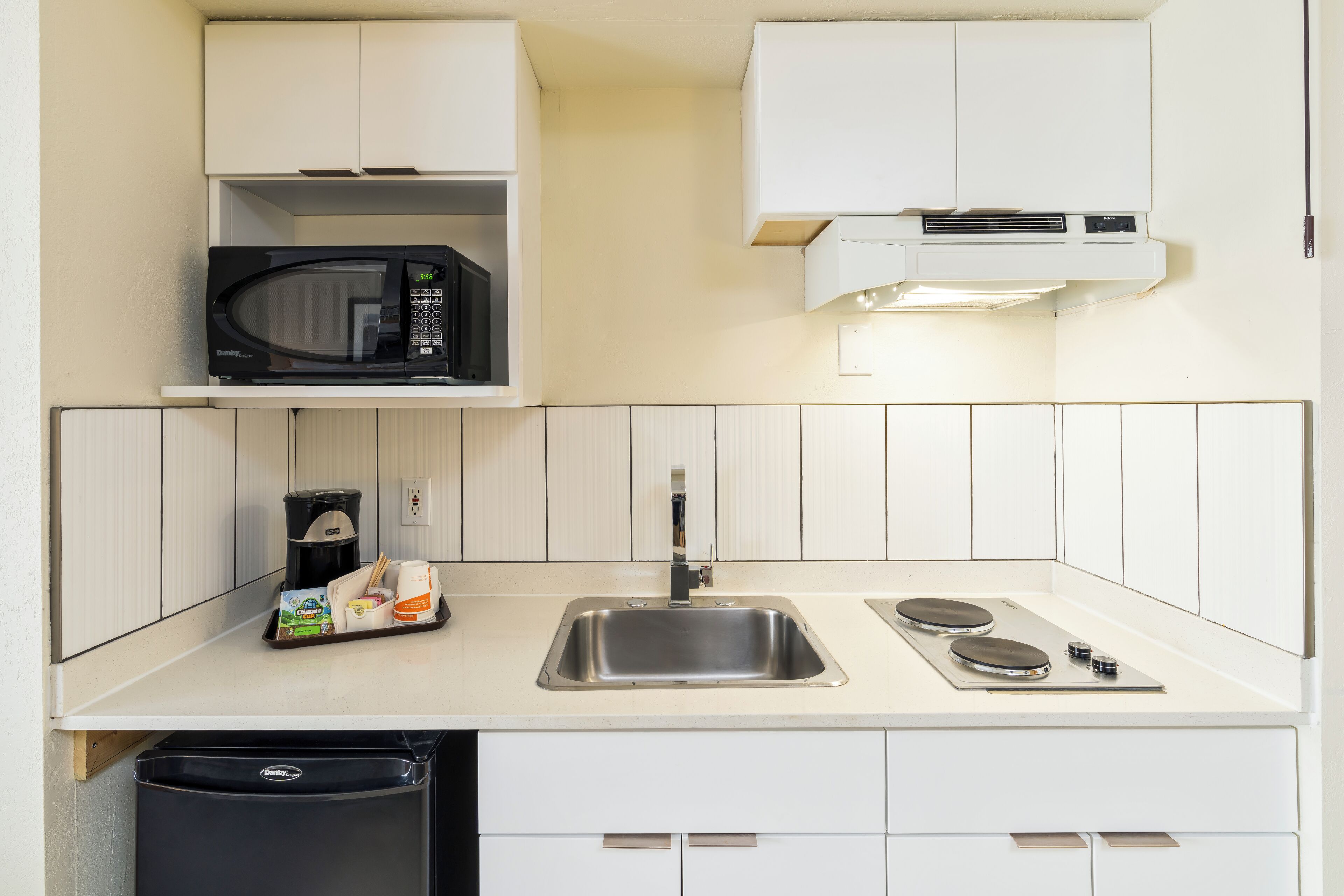 A compact kitchen with a microwave, coffee maker, and sink.