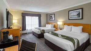 A hotel room with two beds, a desk with a chair, a TV, and a window with curtains.