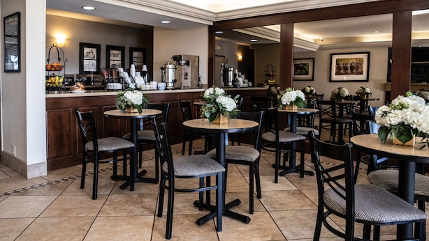 Um restaurante com mesas e cadeiras redondas, um espaço para café e quadros nas paredes.