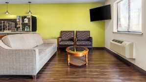 Una sala de estar con un sofá, dos sillones, una mesa de centro, televisor y una ventana con persianas.