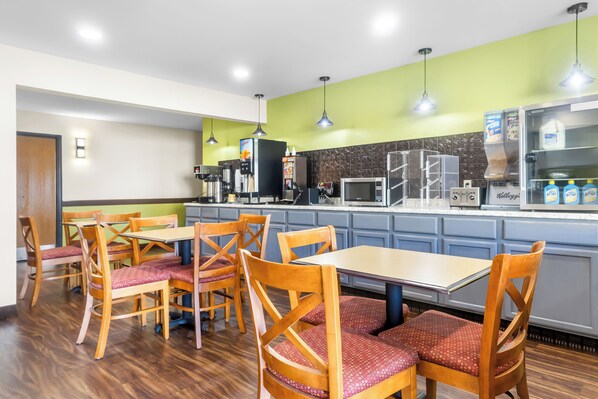 A restaurant with wooden chairs and tables, a counter with a coffee machine, and a milk fridge.
