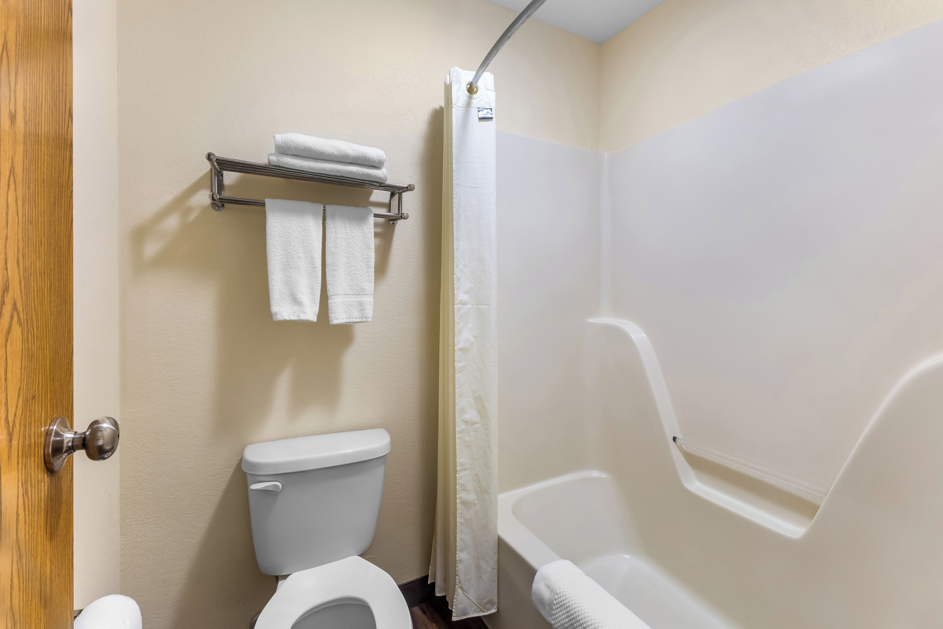 Une salle de bain comprenant des toilettes, une douche avec un rideau et un porte-serviettes avec deux serviettes.