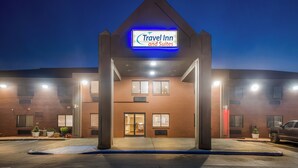 Edificio de Travel Inn and Suites con un letrero iluminado llamativo, fachada de ladrillo y estacionamiento.