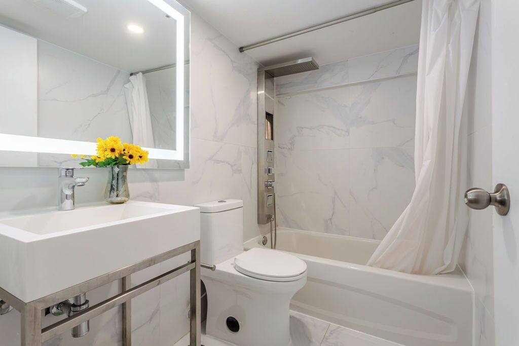Une salle de bain moderne avec un lavabo en marbre blanc, des toilettes et une baignoire.