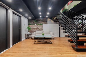 Un espace de vie moderne comprenant un escalier, un canapé, une table basse et un mur en briques.