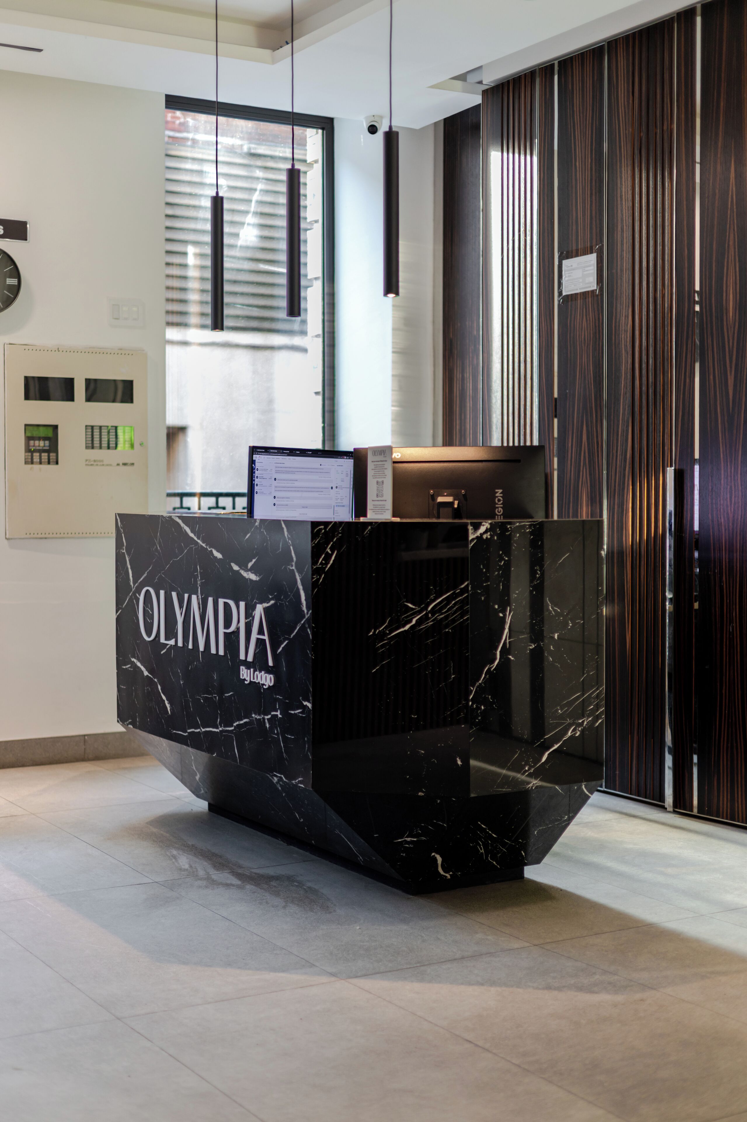 A reception desk with "OLYMPIA By Logo" signage, a computer monitor, and a telephone.