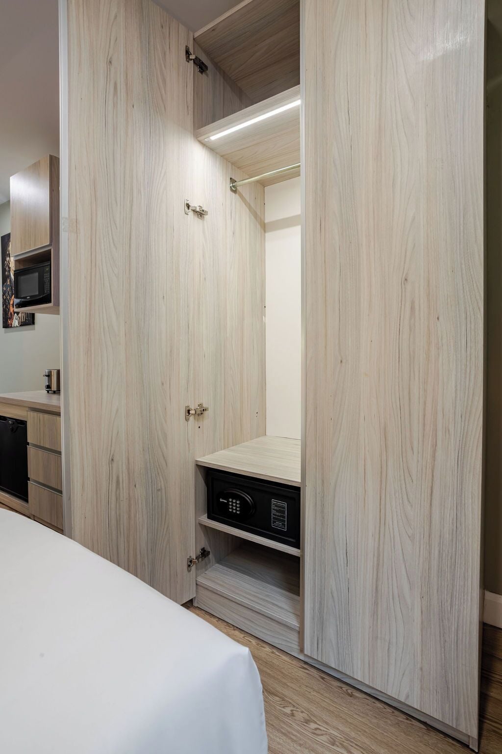 Une chambre à coucher moderne avec une armoire en bois, un lit et un bureau intégré équipé d’un ordinateur.