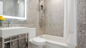 Deluxe kamer, 1 kingsize bed | Badkamer | Een bad/douchecombinatie, een regendouche, gratis toiletartikelen