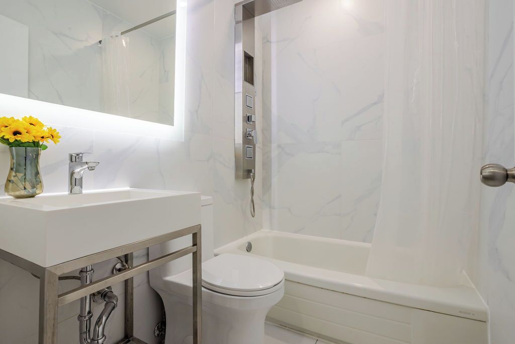 A modern bathroom with a white sink, a toilet, and a bathtub.