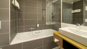 Et moderne badeværelse med badekar, bruser og håndvask.