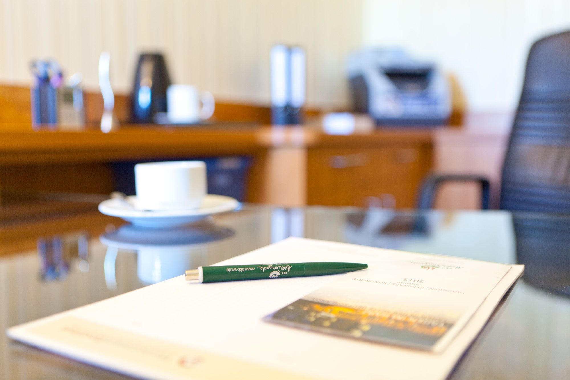 A hotel room with a dining table, a white cup, a green pen, and a menu.