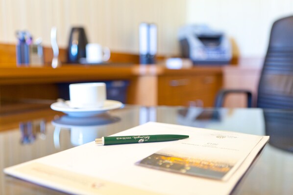 Una habitación de hotel con una mesa de comedor, una taza blanca, un bolígrafo verde y un menú.