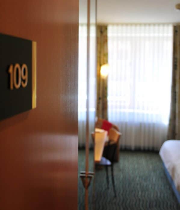 A hotel room with a bed, a chair, and a window with curtains. The room number is 109. - Harzer Kultur- & Kongresshotel Wernigerode (Wernigerode)