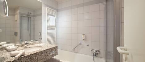 A bathroom with a granite countertop, a large mirror, a shower with a glass door, and a bathtub.