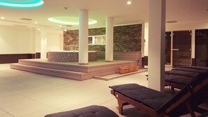Un spa moderno con pared de piedra, zona de recepción y varias camillas de masaje.