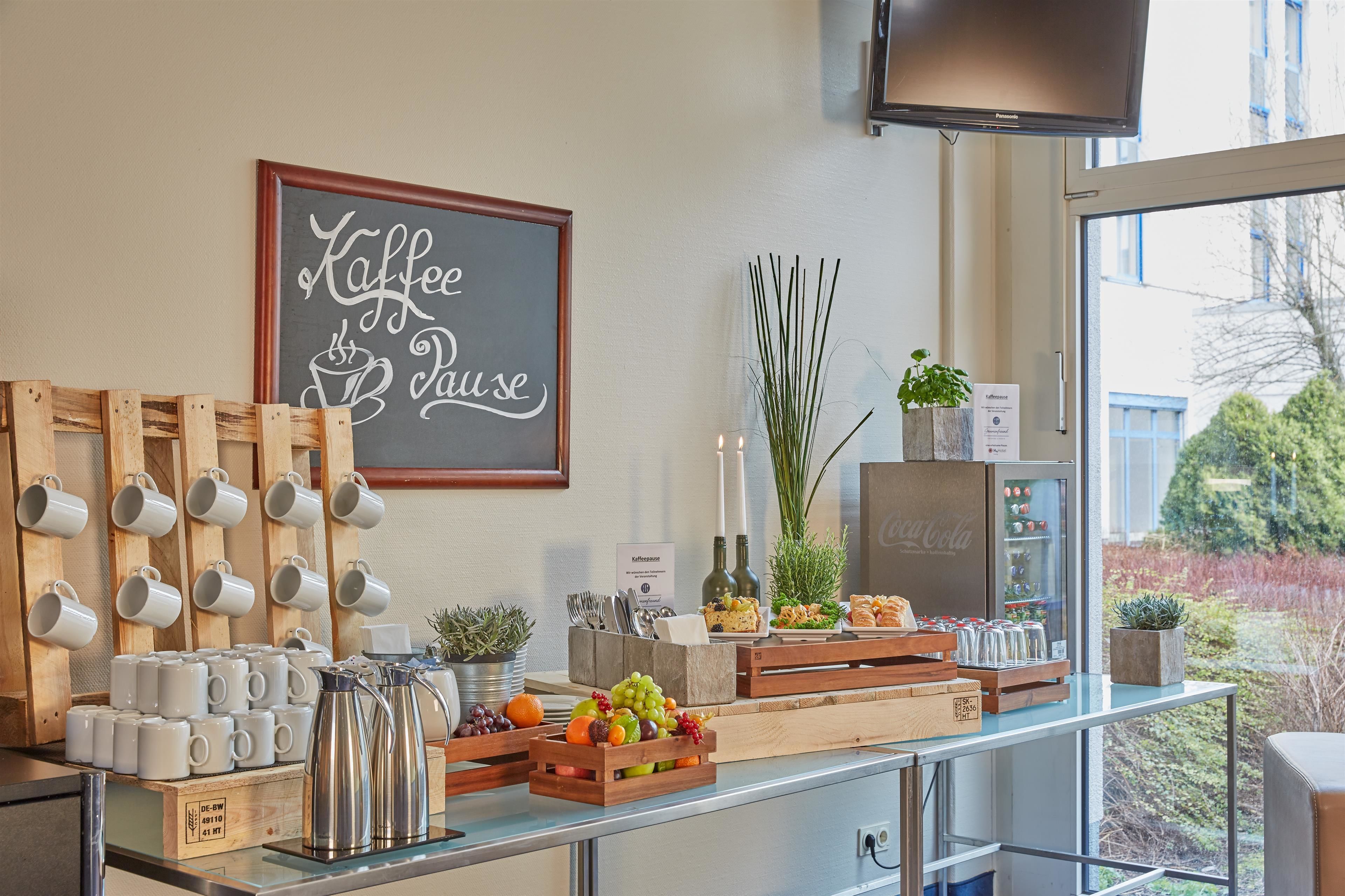 A coffee station with mugs, coffee pots, and a sign that says "Coffee Pause".