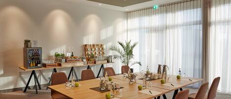 A conference room with a long table, chairs, and a plant.