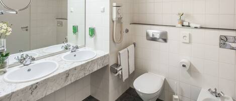 Un baño moderno con dos lavamanos, un inodoro, un bidé y un asiento de bidé.