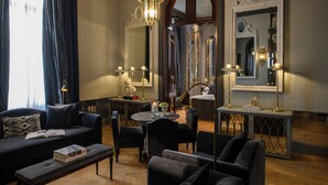 Un salón bien iluminado con un sofá, sillones, una mesa de centro y una zona de comedor con candelabro.