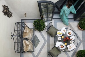 An outdoor dining area with a round table set for a meal, surrounded by cushioned seating and potted plants. - Helvetia & Bristol Firenze – Starhotels Collezione (Florence)