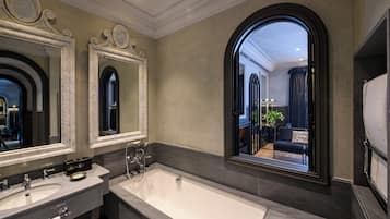 Un baño moderno con dos lavamanos, una bañera grande y un espejo con marco arqueado.